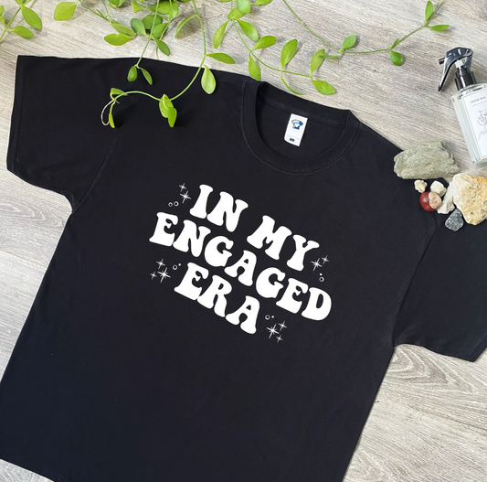 Elevate your bridal style with our 'In my Engaged Era' themed T-shirts and Hoodies! Inspired by the Taylor Swift hit, these garments are a must-have for any Swiftie bride-to-be. Whether you're celebrating your hen weekend or walking down the aisle, our designs add a fun and fashionable touch to your special day. Each item is crafted from 100% cotton and hand-printed to order, ensuring both comfort and quality. With a range of sizes and colors available, you can find the perfect fit for your bridal party. Ma